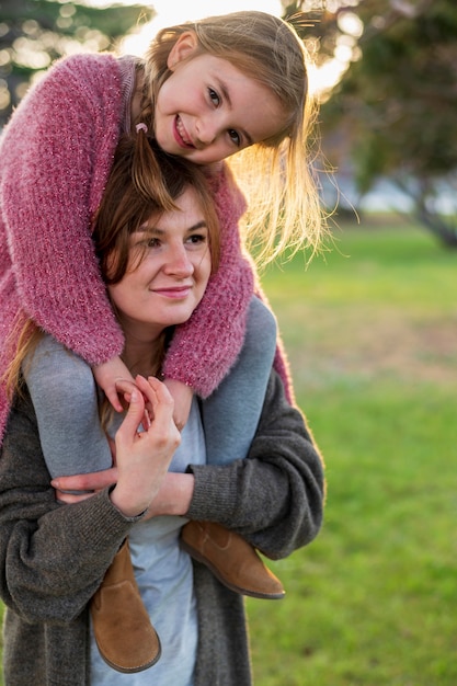 Lovely mother carrying girl on shoulders