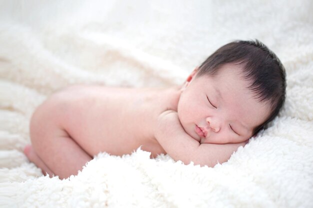 Lovely newborn Asian baby sleeping on furry blanket