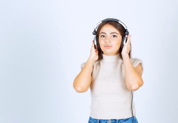 Lovely pretty woman looking at the camera and listening the music in headphones.