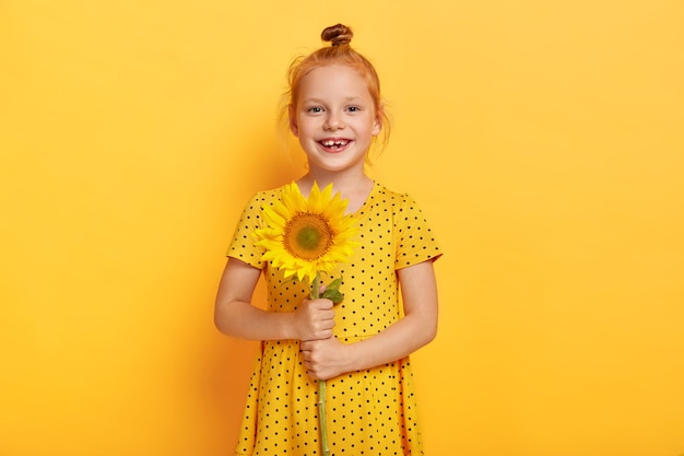 Lovely red haired girl holds sunflower