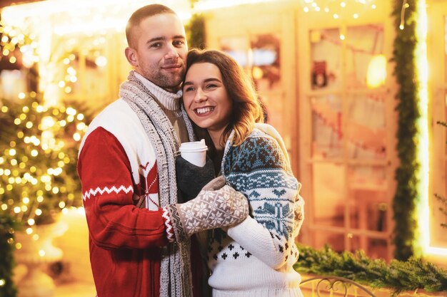 Lovely romantic people feels very happy together on Christmas Eve inbetween festive lights.