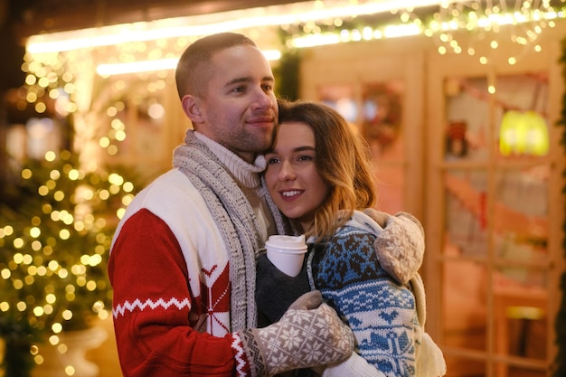 Lovely romantic people feels very happy together on Christmas Eve inbetween festive lights.