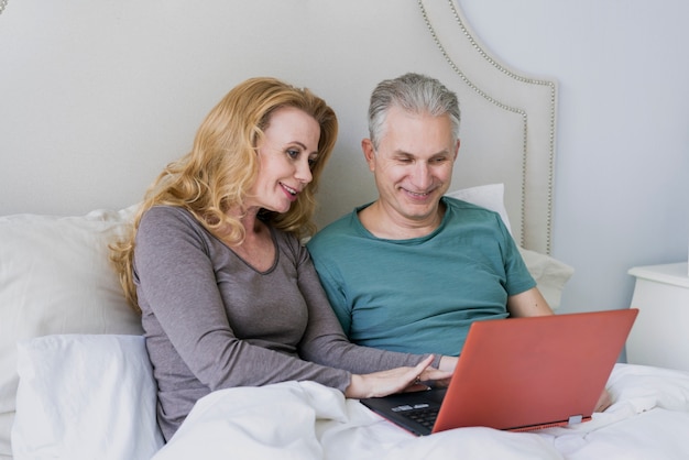 Free photo lovely senior man and woman with laptop in bed