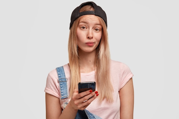 Lovely stylish female youngster holds modern smart phone