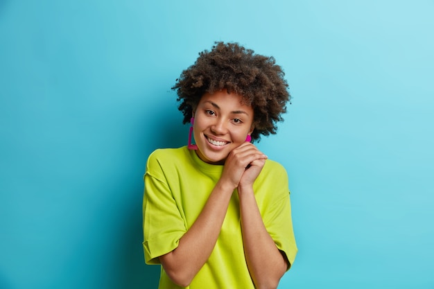 Lovely teenager girl has tender smile keeps hands near face