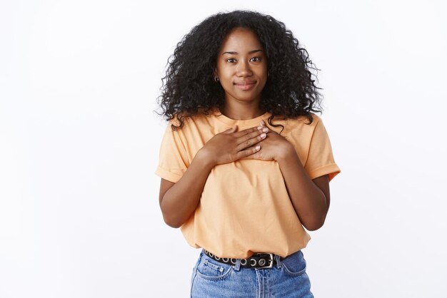 사랑스러운 아프리카계 미국인 소녀는 감사의 표시로 손바닥을 가슴으로 누릅니다.