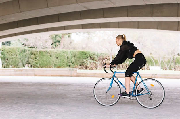 Lovely woman on bicycle under bridge