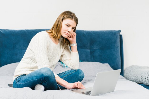 Lovely woman browsing laptop on bed