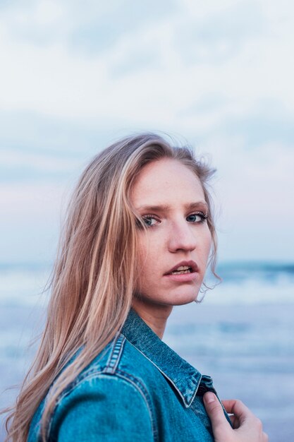 Lovely woman in denim jacket near sea