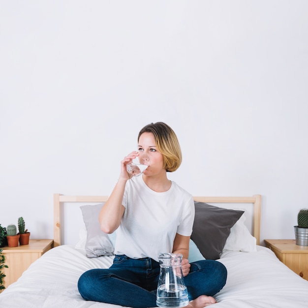 Free photo lovely woman drinking water on bed