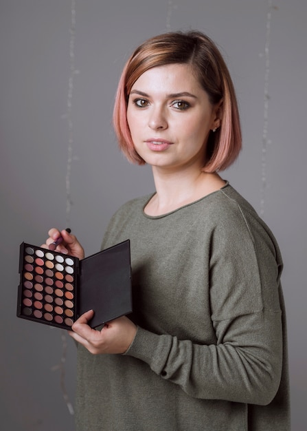 Free photo lovely woman holding eyeshadow palette