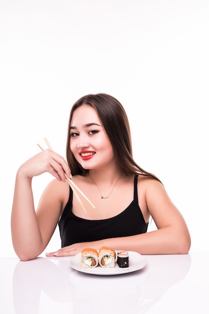 Милая женщина готова съесть вкусные суши роллы с помощью деревянных палочек для еды, изолированных на белом