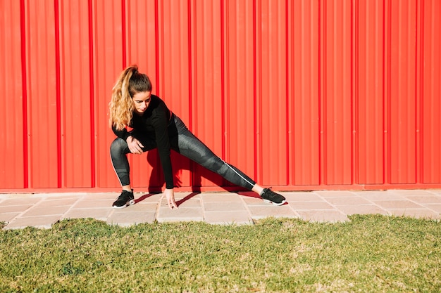 Lovely woman lunging near red wall