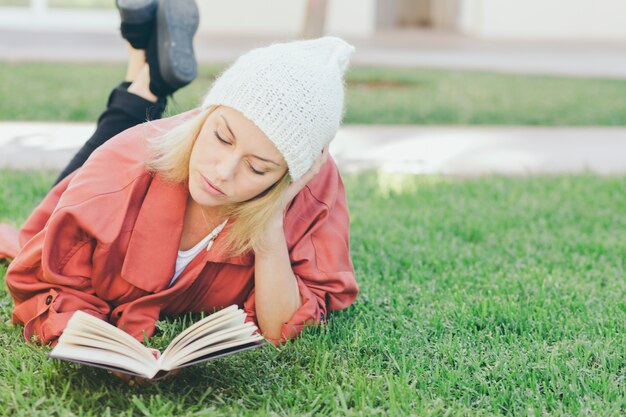 Lovely woman reading book on grass