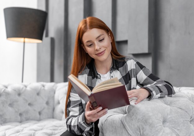 Симпатичная женщина читает книгу в помещении