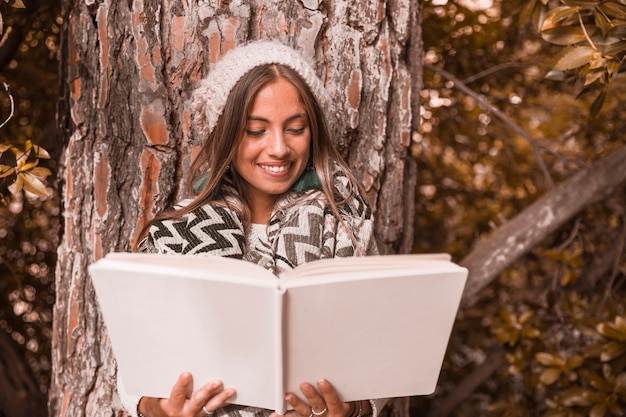 Free photo lovely woman reading book near tree