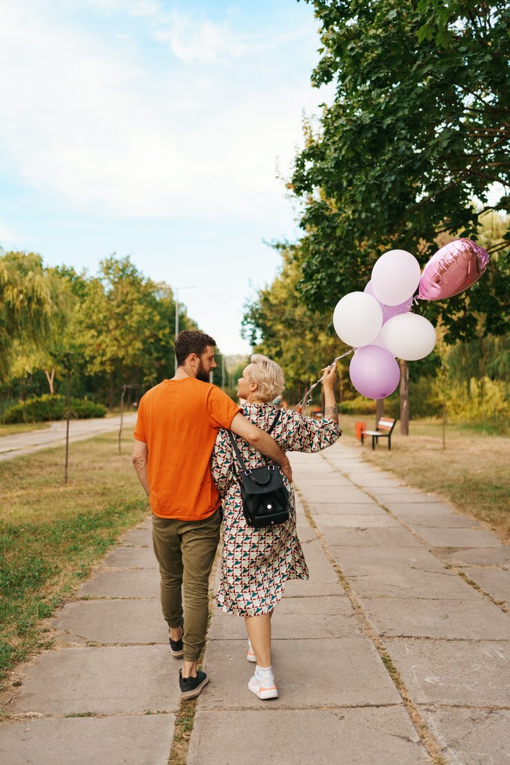 Free Photo lovely woman with backpack and casual man walking happy with pink balloons in the park. freedom and healthy women concept.