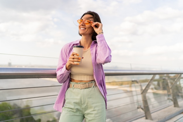 Lovely woman with short hairstyle walking on modern bridge in windy summer day