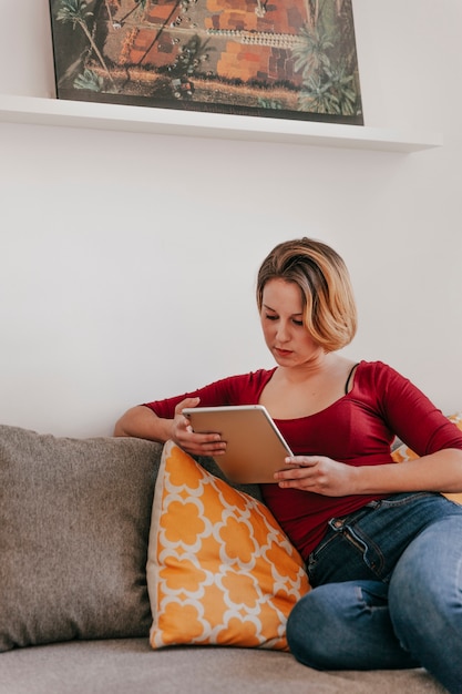 Free photo lovely woman with tablet on couch