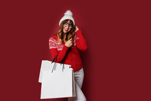 Lovely woman with wavy hairs standing with white shopping bags