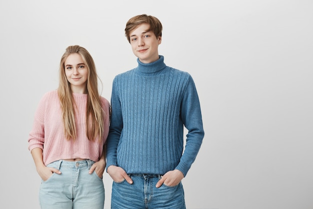 Lovely young caucasian boy and girl wearing knitted sweaters and jeans