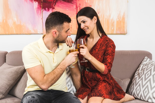 Free photo lovely young couple holding wineglasses looking at each other