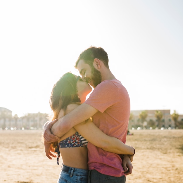 素敵な若いカップルがビーチで晴れた日にキス