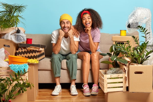 Free photo lovely young couple sitting on the couch surrounded by boxes