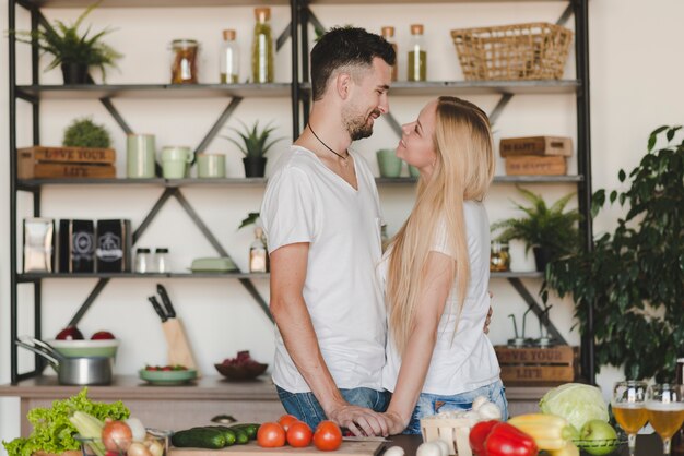 Lovely young couple standing behind the kitchen counter looking at each other
