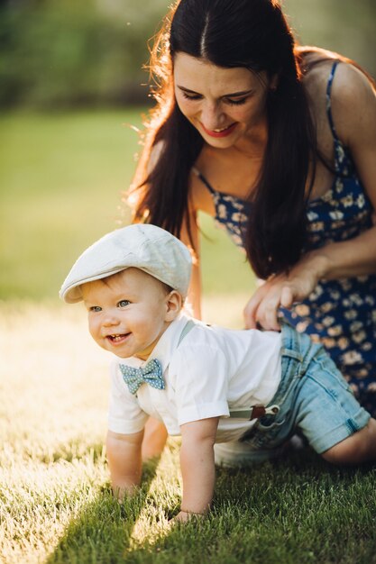 La giovane madre adorabile va a fare una passeggiata con il suo piccolo bambino caucasico nel parco