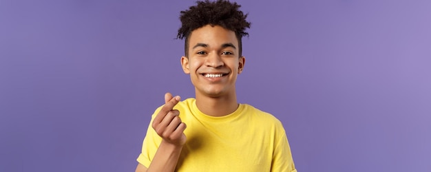 Lovely young romantic boyfriend guy showing korean heart with fingers and smiling like someone being