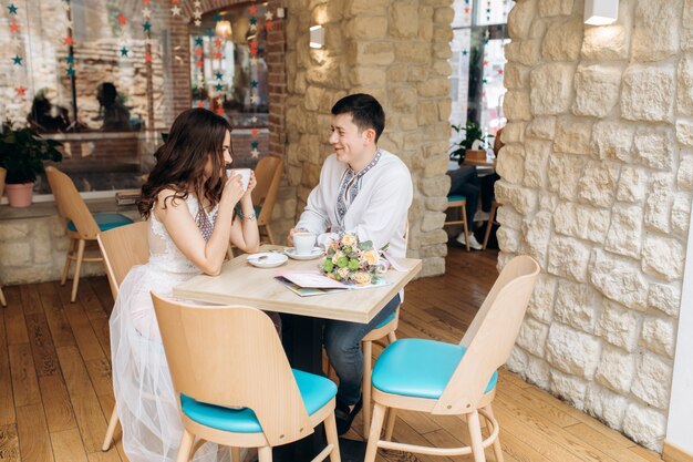 Lovely young wedding couple sits at a dinner table in a cosy cafe