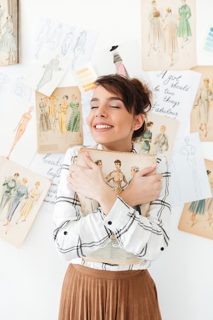 Бесплатное фото Симпатичная молодая женщина фахион дизайнер держит ее альбом