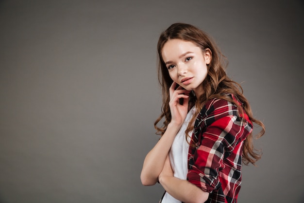 Free photo lovely young woman in plaid shirt standing and posing