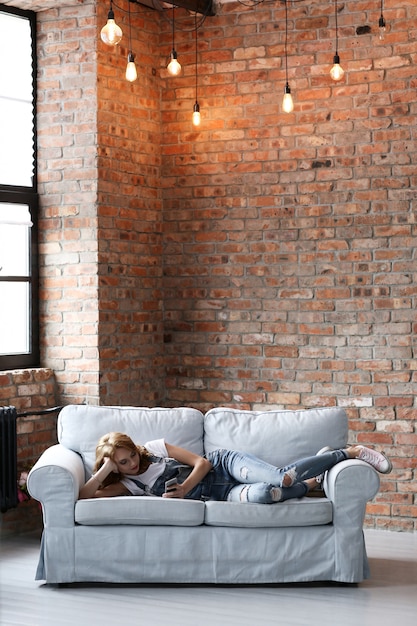 Lovely young woman resting on the couch, interior living room