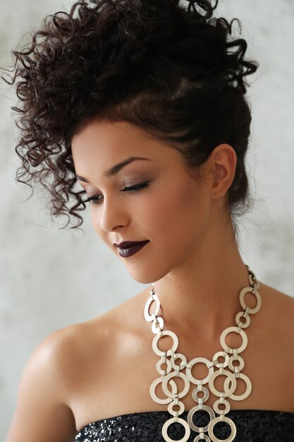 Lovely young woman with black curly hair and black shiny dress