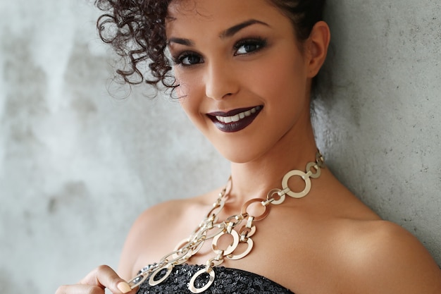 Free photo lovely young woman with black curly hair and black shiny dress