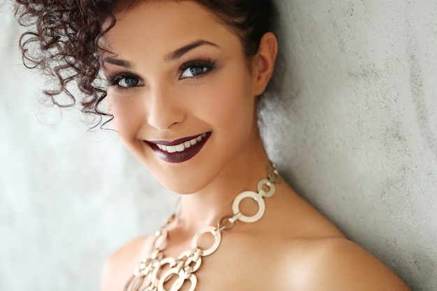 Free photo lovely young woman with black curly hair and black shiny dress