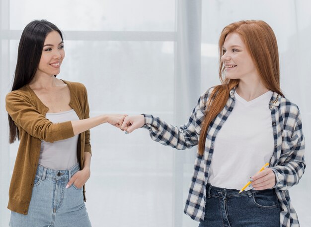 Lovely young women touching fists