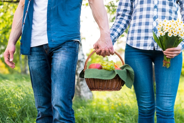 Lovers holding picnic basket on meadow