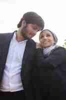 Free photo loving arabic couple walking together. woman with covered head and bright make-up leaning on boyfriends shoulder, looking up. love, affection concept