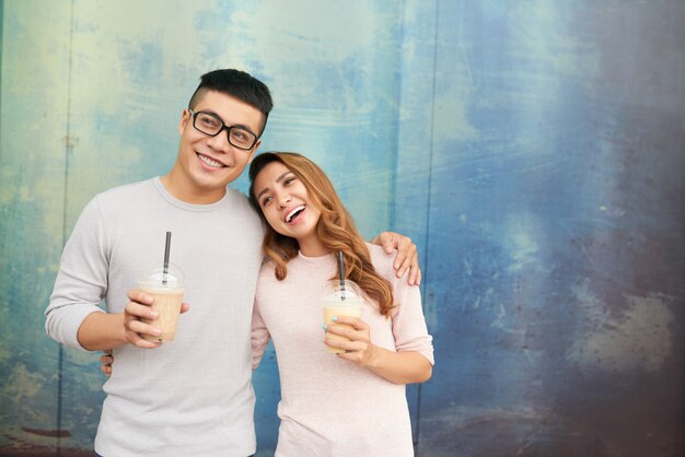 Loving couple cheerfullly smiling holding milkshakes