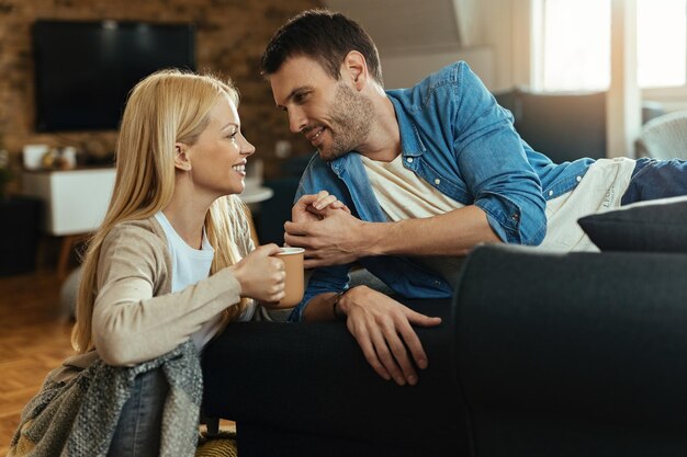 Loving couple communicating while holding hands and looking at each other at home