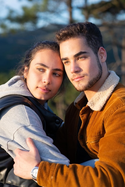 Loving couple of hikers in autumn. Man and woman in casual clothes sitting at peak, looking at camera. Nature, activity, hobby concept