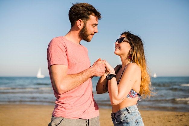 愛情のあるカップルがビーチでお互いの手の地位を保持