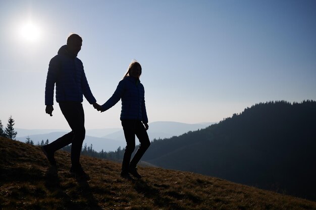 Loving couple holding hands and walking down the hill