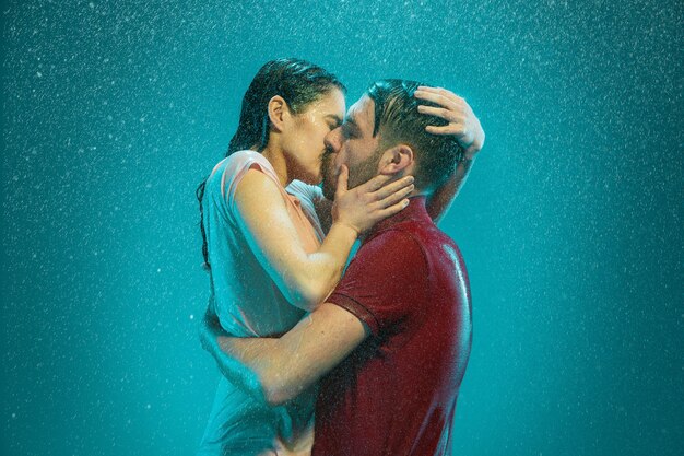 The loving couple kissing in the rain on a turquoise background