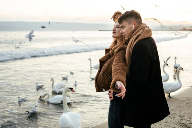 Loving couple listening to music on earphones on the beach in winter