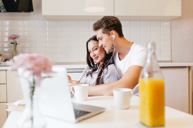 Loving couple listening music together during breakfast in cozy kitchen