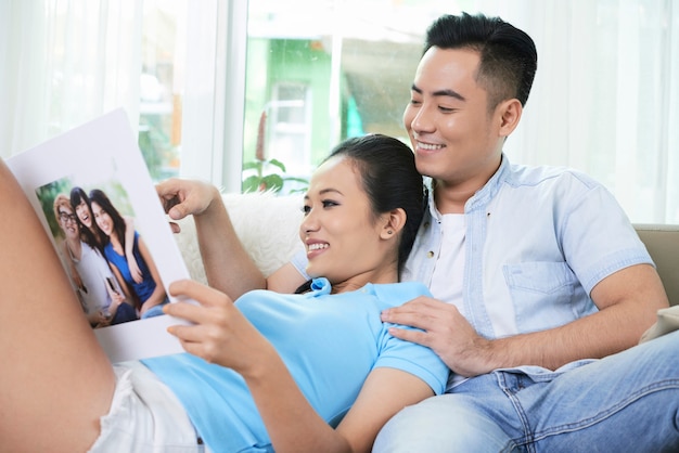 Loving couple looking photo album on sofa